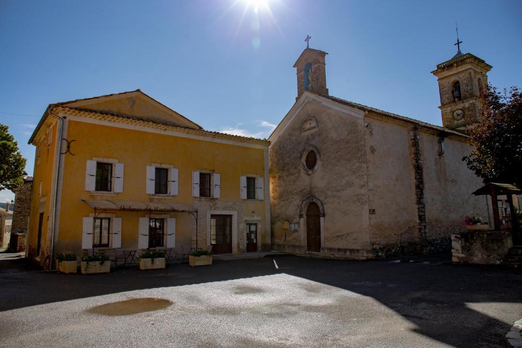 un vecchio edificio con una torre e una chiesa di L’auberge de Montsalier a Le Plan