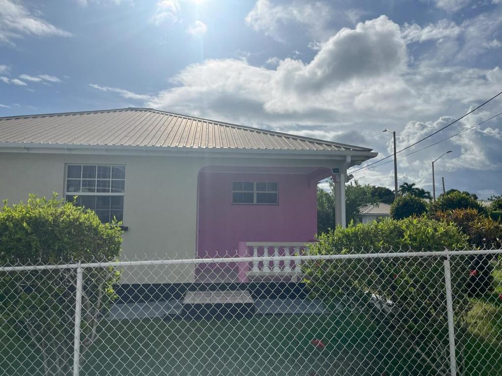 une maison rose et blanche avec une clôture dans l'établissement Jo'Marion's Place, à Saint James