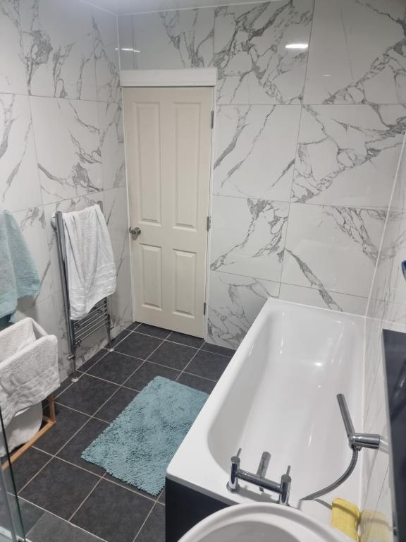 a bathroom with a white tub and marble walls at Fir Trees in Blackpool
