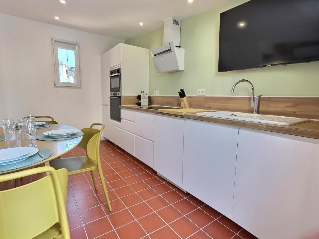une cuisine avec des armoires blanches et une table avec des chaises dans l'établissement Le chateau de ma mère- climatisé -duplex- 4 personnes, à Aubagne