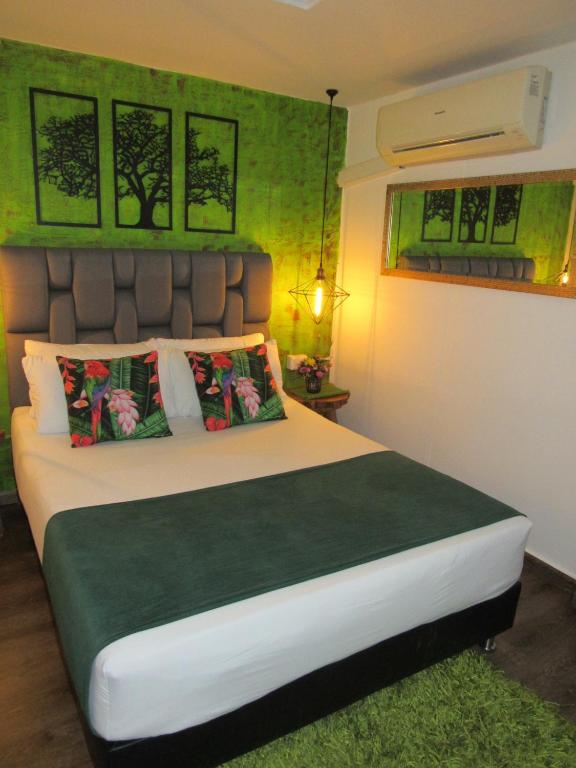 um quarto com uma cama grande com paredes verdes em The Garden Lleras 10 em Medellín