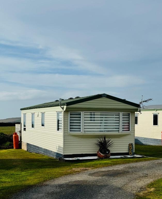 a small white house with a porch at Meadow & Tide in Saint Merryn