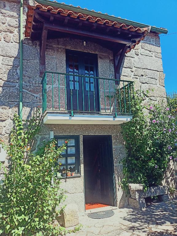 a stone building with a balcony and a door at Casa da Calçada in Arcos de Valdevez