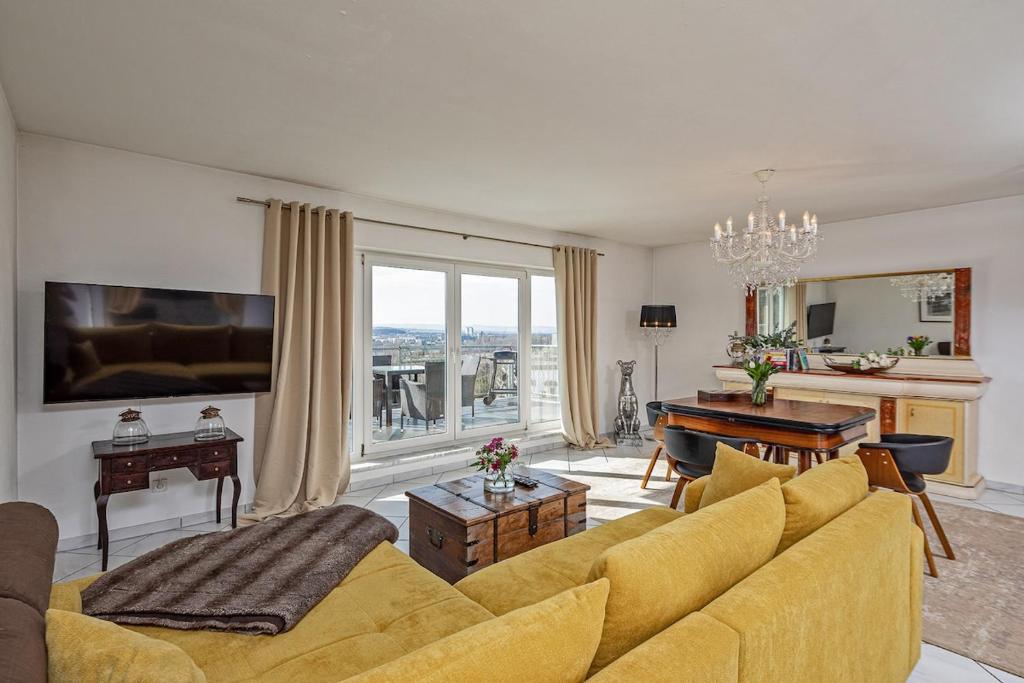a living room with a yellow couch and a piano at Koblenz Rheinblick Penthouse in Vallendar