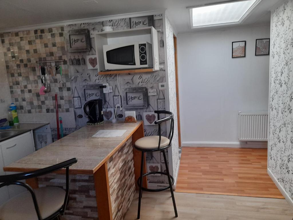 eine Küche mit zwei Barhockern und einer Mikrowelle in der Unterkunft Departamento Kran in Punta Arenas