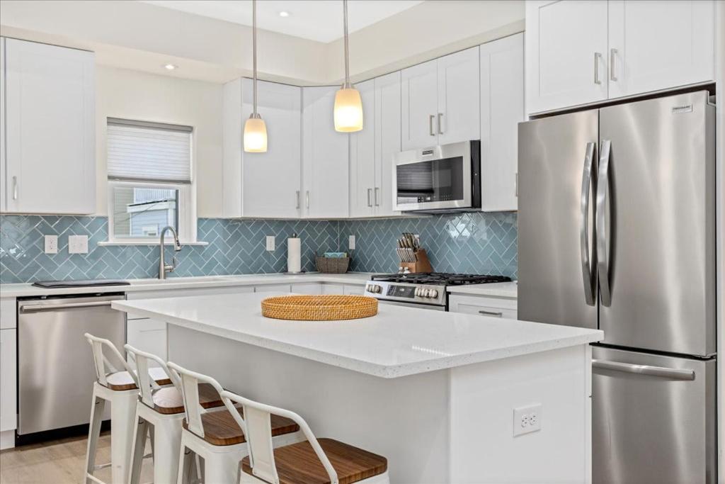 a kitchen with white cabinets and a stainless steel refrigerator at Spacious Newly Built Townhouse 2 blocks to Beach in Ventnor City