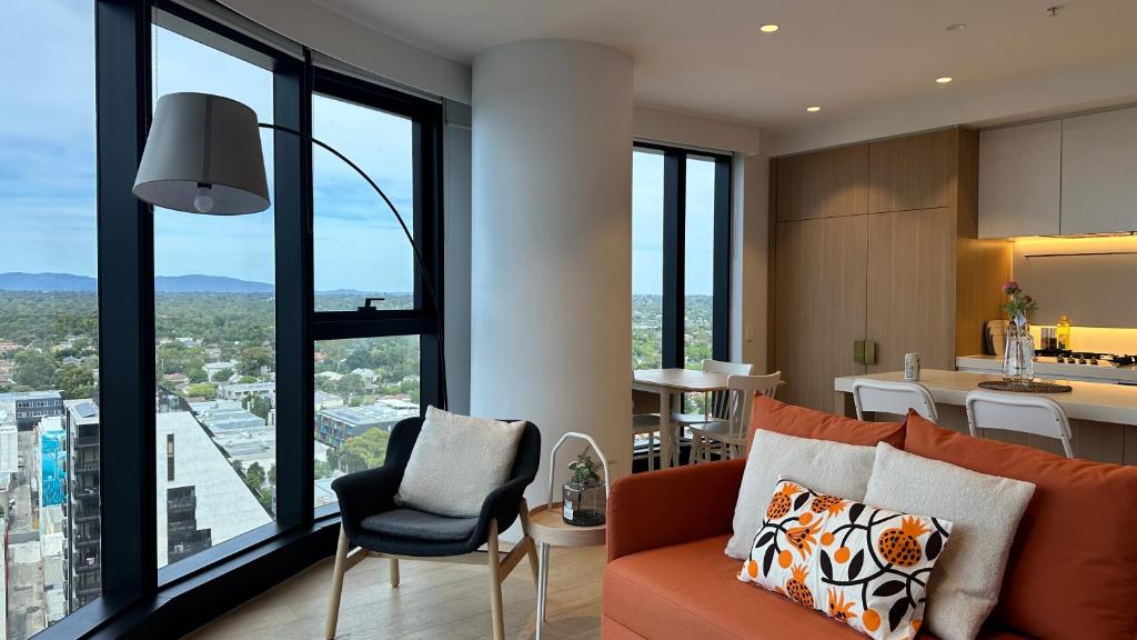 a living room with an orange couch and a kitchen at Sky One Harmony in Box Hill