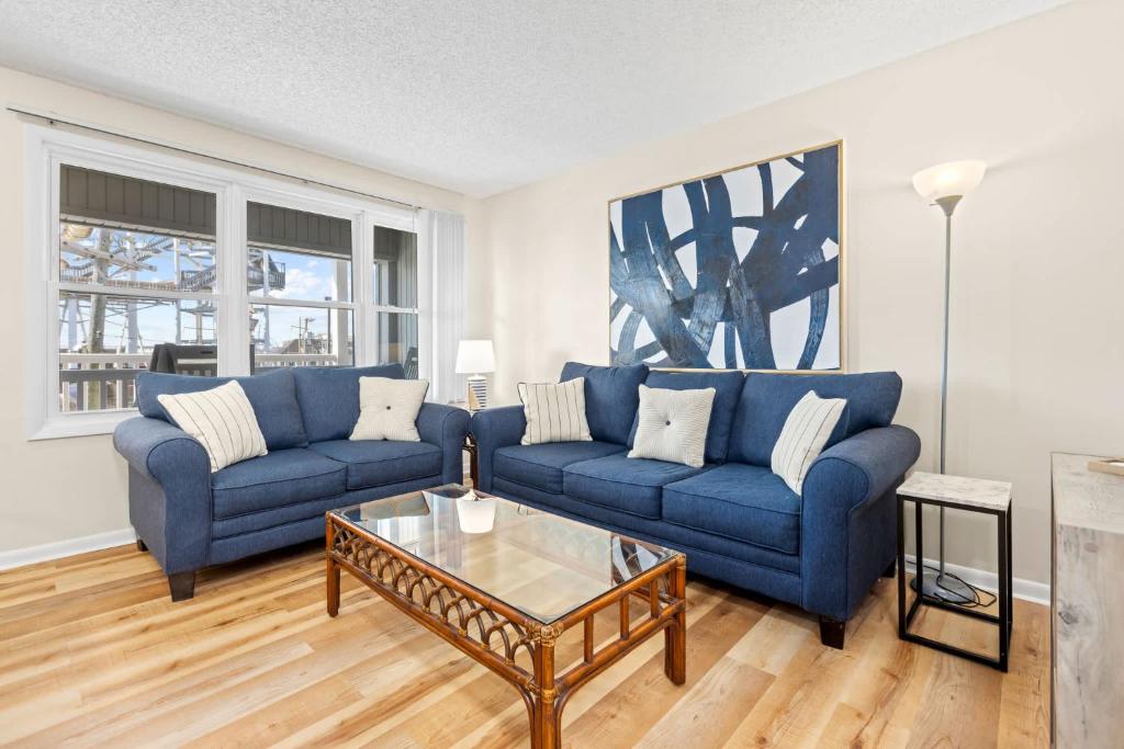 a living room with two blue couches and a coffee table at Modern Condo Just Steps from the OC Boardwalk in Ocean City