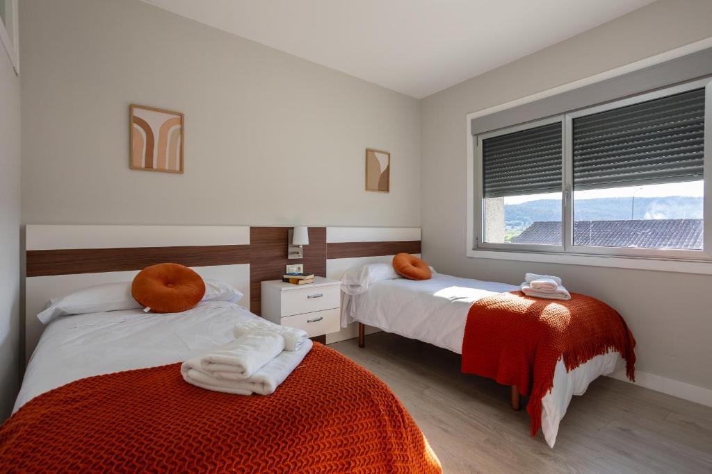 a bedroom with two beds and a window at Veigas de Iria - Apartamento Turístico VUT in Padrón