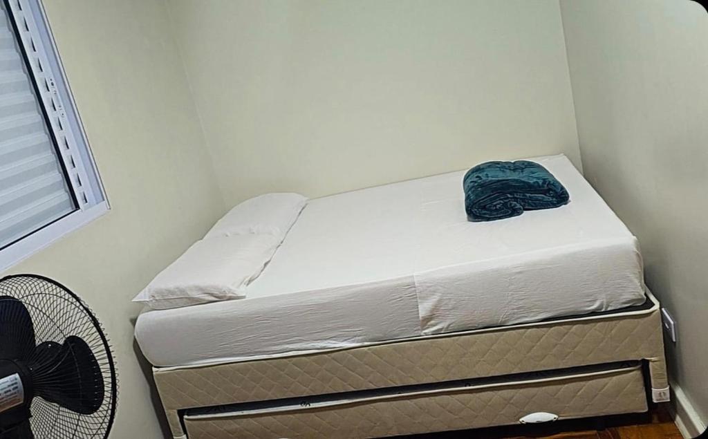 a small bedroom with a bed with a blue blanket on it at Le house hostel in São Paulo
