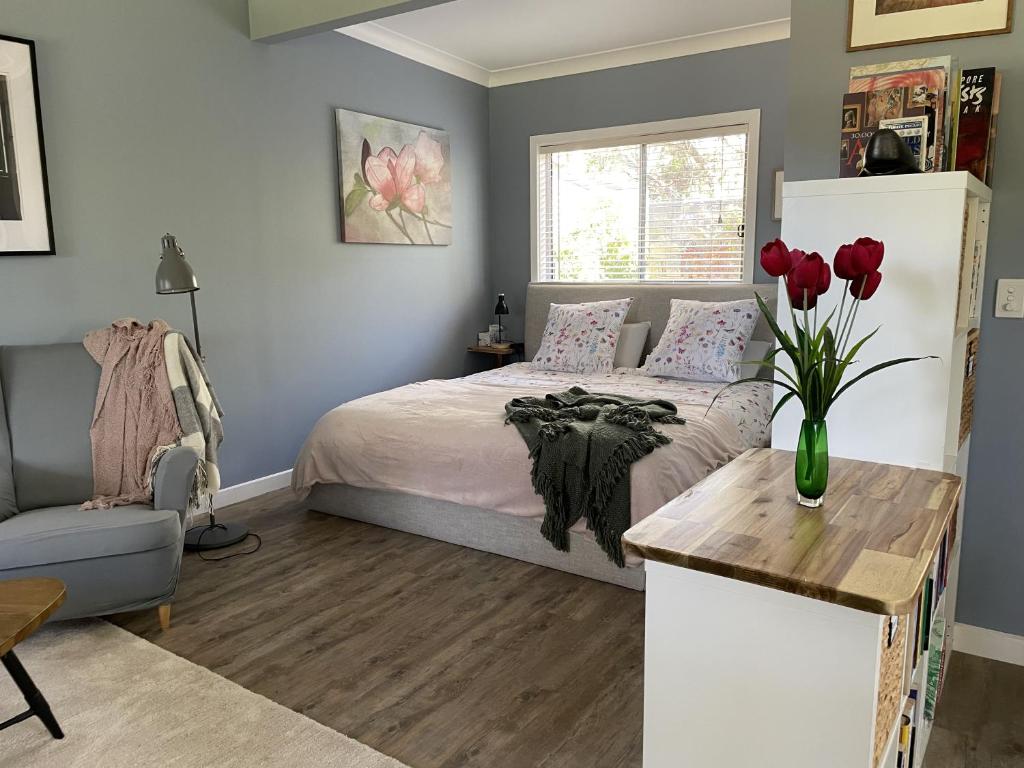 ein Schlafzimmer mit einem Bett und einer Vase aus roten Tulpen in der Unterkunft Blue Gate Cottage in Indigo Upper