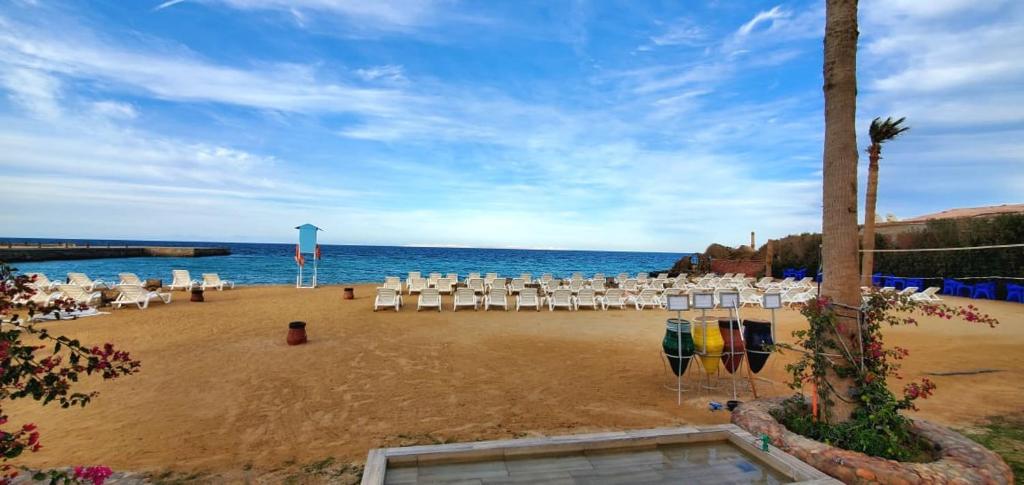 a beach with a bunch of chairs and the ocean at Seaview 2 Bedroom Private Deluxe Condo at Juliana Beach Resort B2-09 in Hurghada