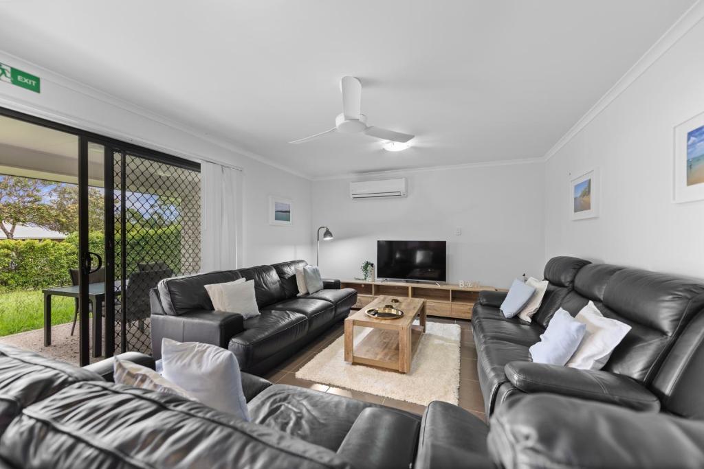 a living room with black leather furniture and a flat screen tv at Charming 3-Bed Home Near Sunshine Coast in Caloundra West