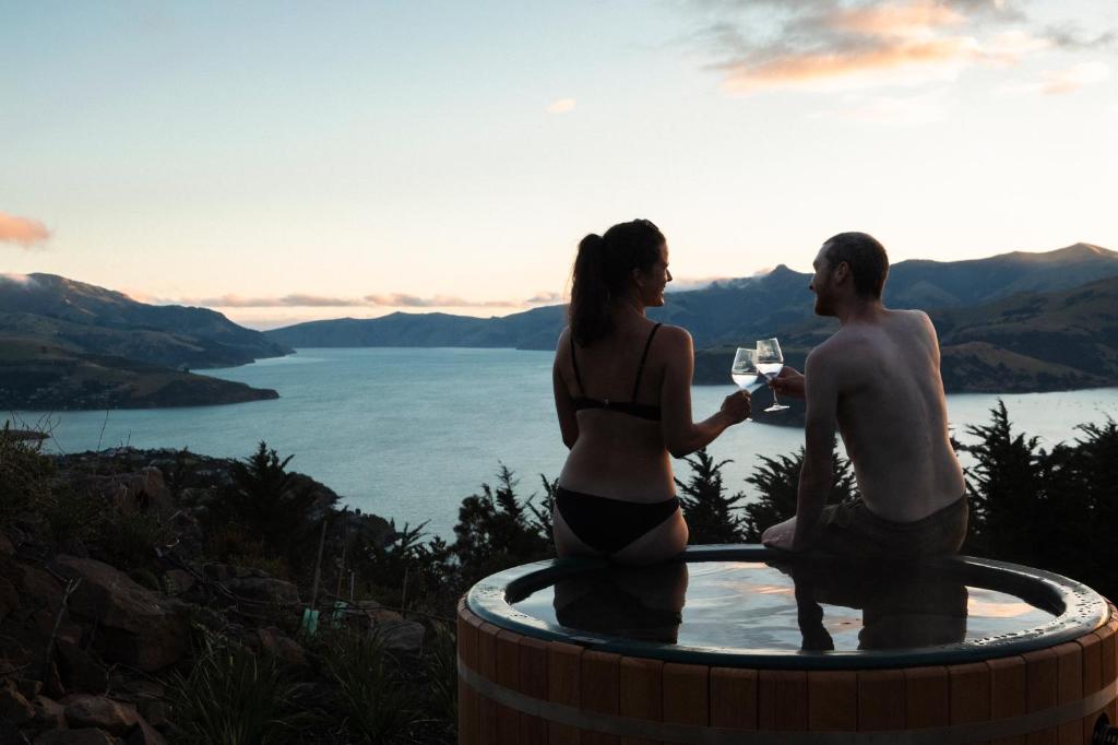 a man and woman standing in a hot tub with a glass of wine at Kūkupa Matairangi at Akaroa Lavender in Akaroa