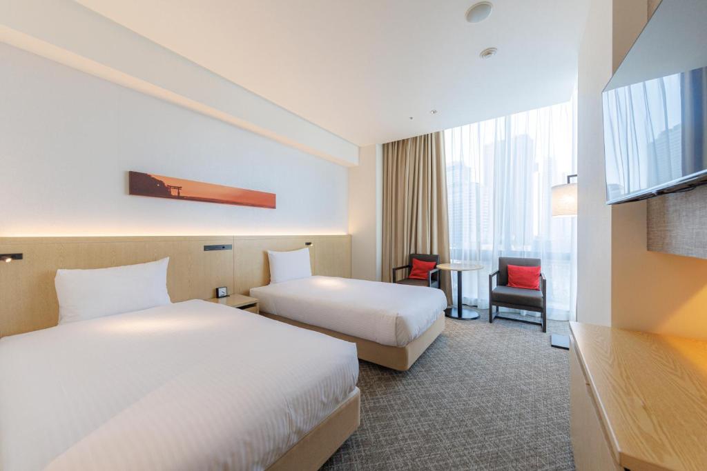 a hotel room with two beds and a table at JR Kyushu Hotel Blossom Shinjuku in Tokyo