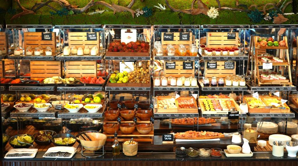 A densely arranged buffet display of fruit, pastries, breads, and prepared dishes.