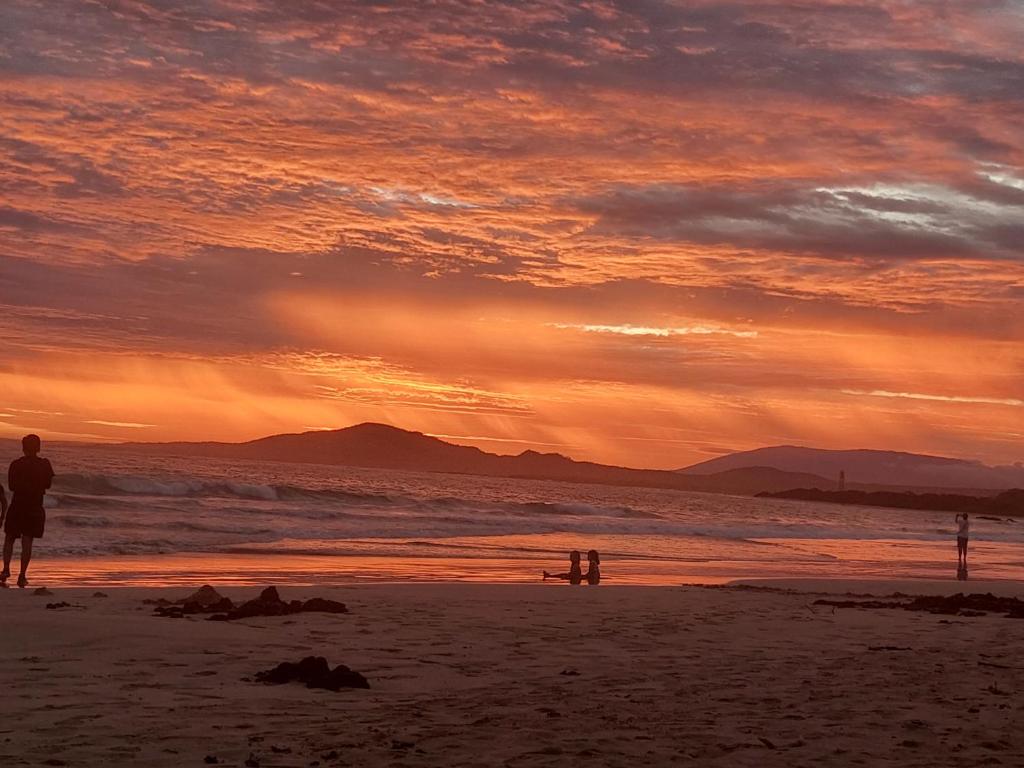 una persona parada en la playa al atardecer en Canelita house, en Puerto Villamil