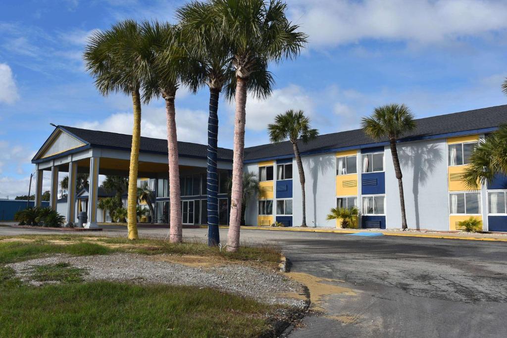 a building with palm trees in front of it at Super 8 by Wyndham Biloxi in Biloxi