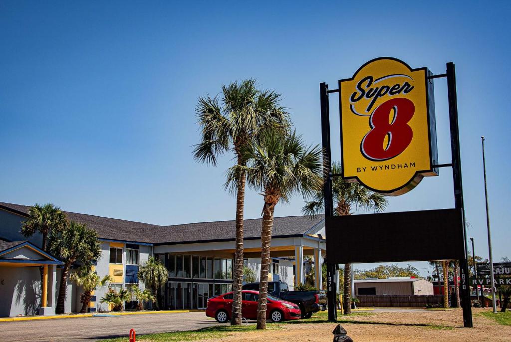a sign for a super motel with palm trees at Super 8 by Wyndham Biloxi in Biloxi
