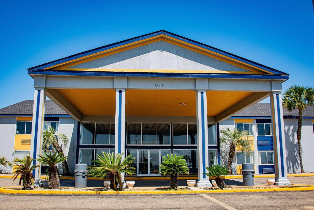 a building with palm trees in front of it at Super 8 by Wyndham Biloxi in Biloxi