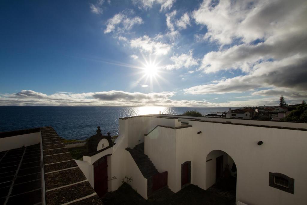 ein Gebäude mit der Sonne am Himmel und dem Ozean in der Unterkunft Casa da Rocha Quebrada in Lagoa