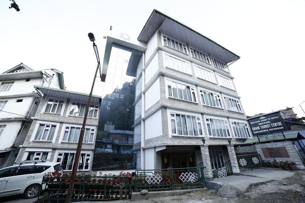 a tall white building with a car parked in front of it at Hotel Sikkim Tourist Centre in Pelling