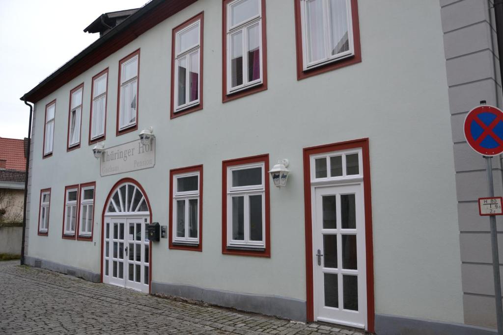a white building with windows and doors on a street at Pension Thüringer Hof Hildburghausen in Hildburghausen