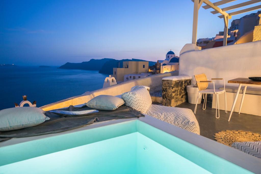 two people lounging on the edge of a pool at Canvas Suites in Oia