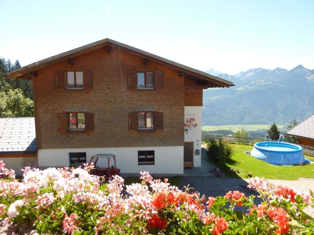 una casa de ladrillo con piscina y flores en Berghof Burtscher, en Ludesch