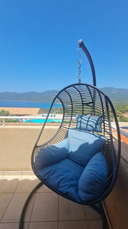 d'une chaise en osier avec des oreillers bleus sur le balcon. dans l'établissement T2 vue mer clim dans résidence 3 piscine chauffée saison & plage à pied, à Serra-di-Ferro