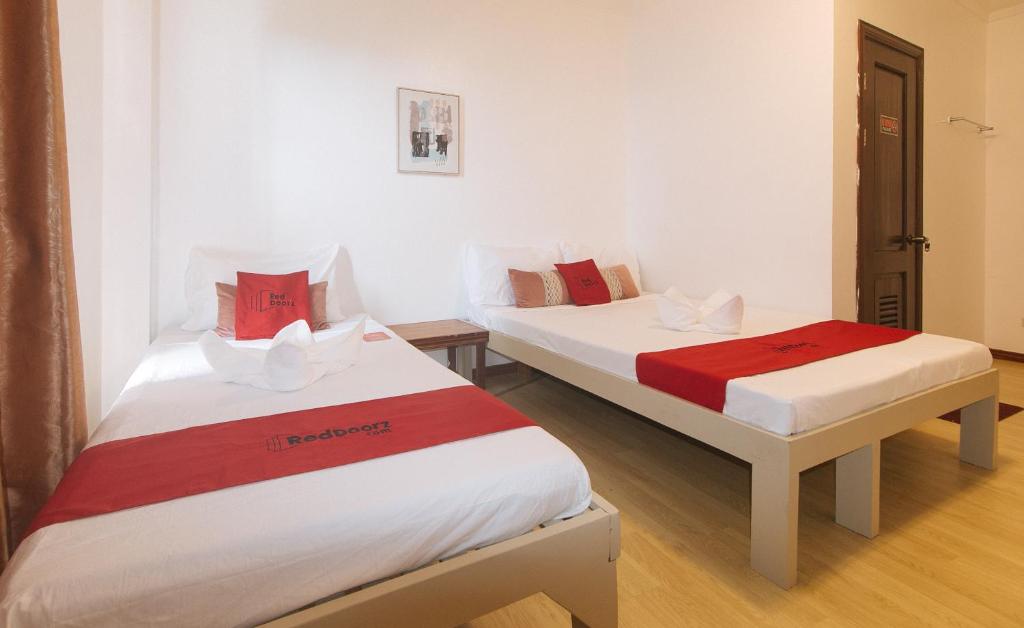 two beds in a room with white and red sheets at RedDoorz at Garvs Boutique Hotel Boracay in Boracay