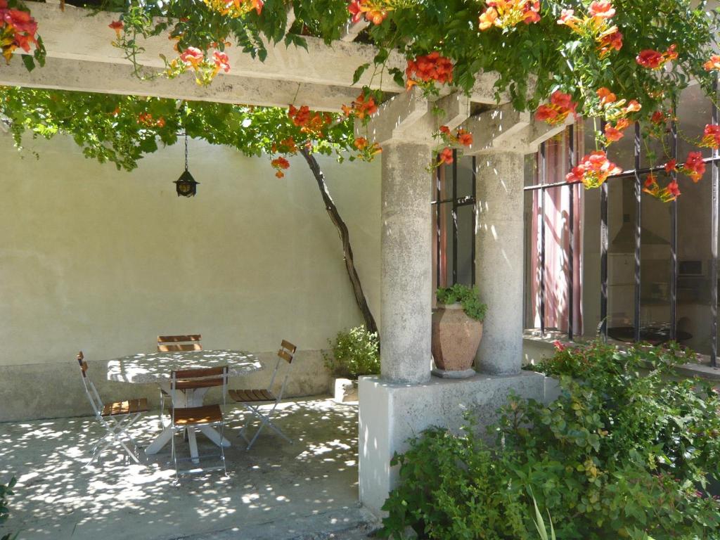 アヴィニョンにあるLe Mas De La Verdiereの木の下にテーブルと椅子のあるパティオ