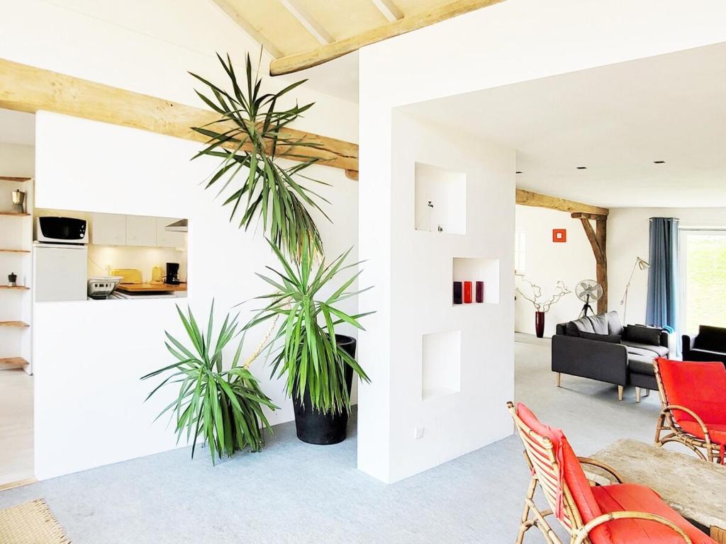 un salon avec des murs blancs et une grande plante dans l'établissement Cottage familial, grand jardin, toboggan, barbecue, à Beurizot
