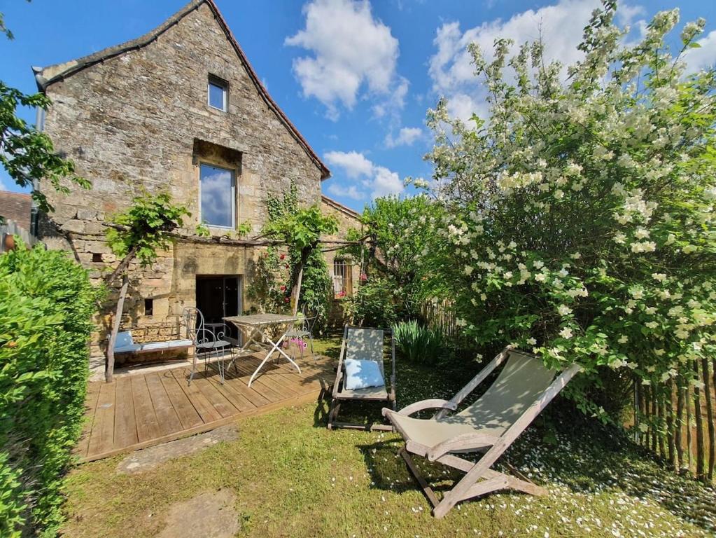 un jardin avec deux chaises longues et une maison dans l'établissement Maison de charme entre Château et Rivière Dordogne - Périgord, à Castelnaud-la-Chapelle