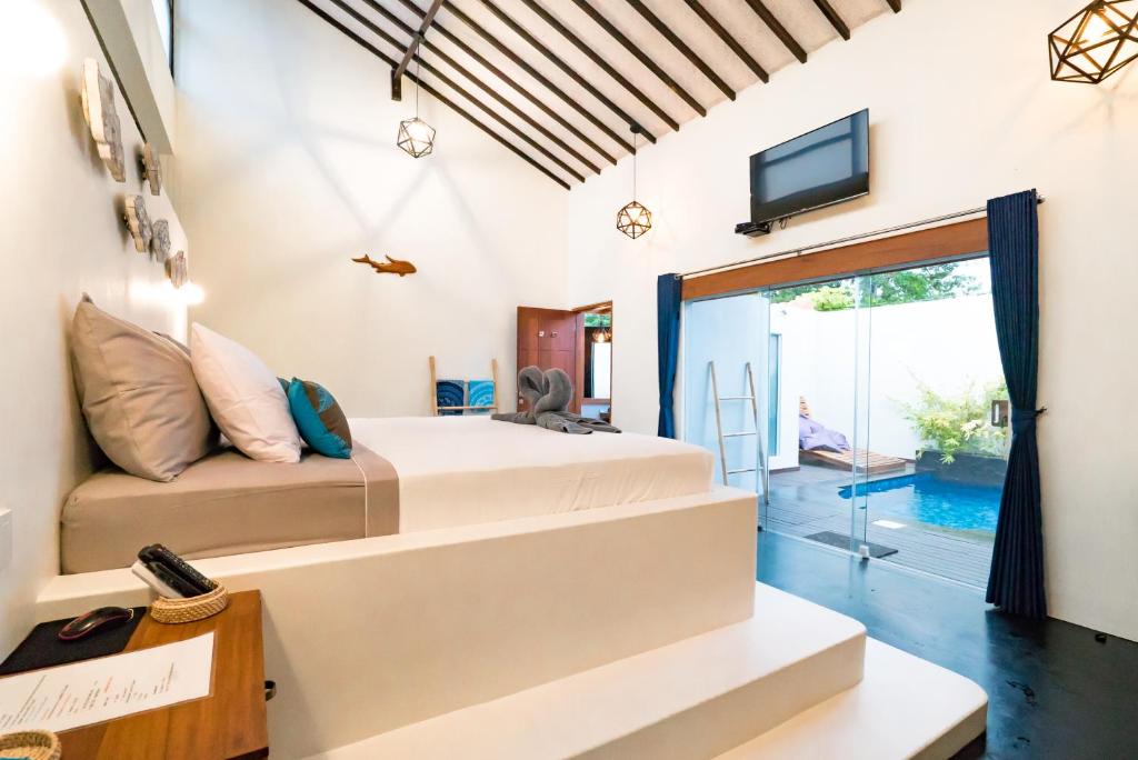 a bedroom with a bed and a tv on the wall at Stay Shark Villas Gili Air in Gili Islands
