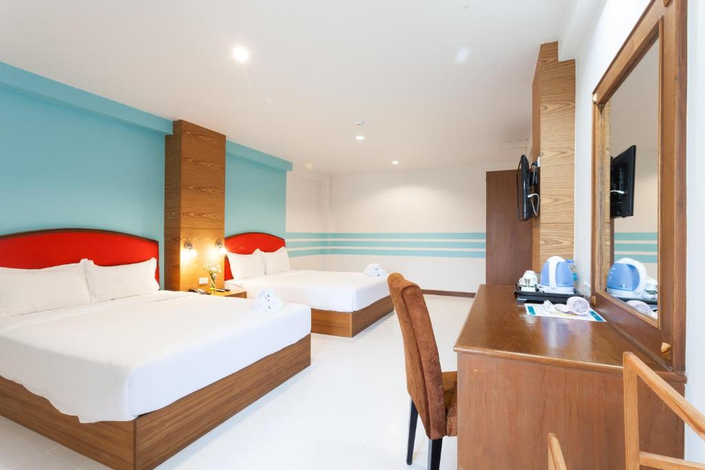 A bright twin room pairs two beds with a built-in desk, mirror and beverage station.
