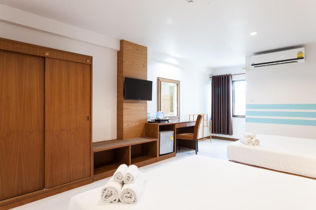A wider bedroom view shows a bed, wardrobe, desk, minibar and curtained window.