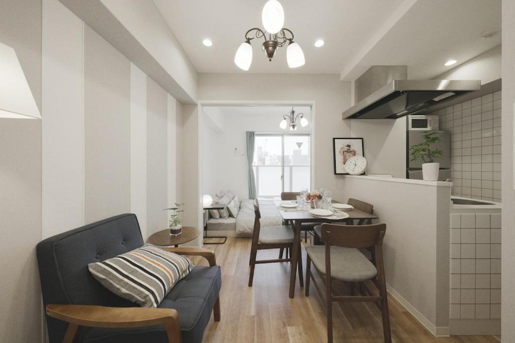a kitchen and dining room with a blue couch and a table at In the heart of Osaka City, with the large studio sunrise, you will have the best time for your trip in Osaka