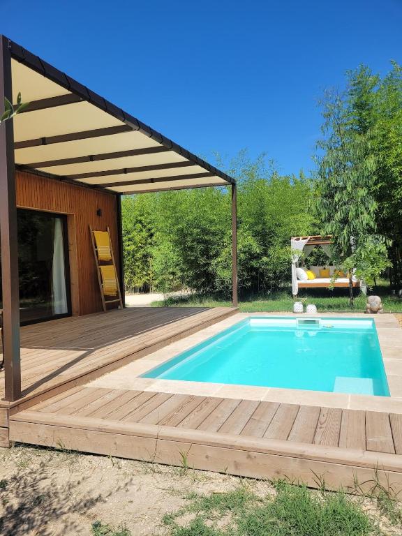 une piscine avec une terrasse en bois et une maison dans l'établissement La Cabane de Cinette, à Vallabrègues