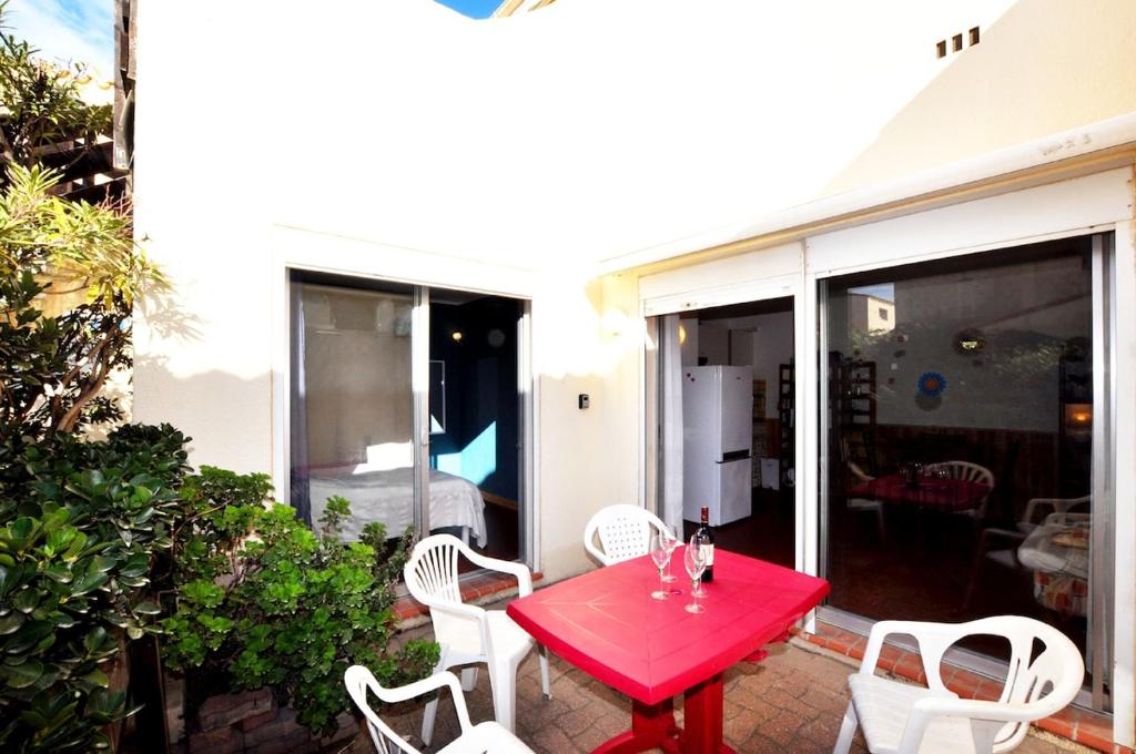 - une table rouge et des chaises blanches sur la terrasse dans l'établissement Plain-pied près du Lydia - Patio, wifi & parking, au Barcarès
