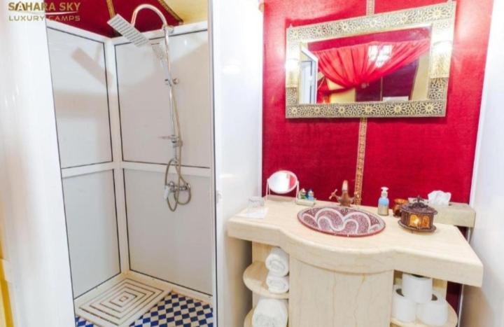 un bagno rosso con lavandino e doccia di Merzouga Nice luxury Camp a Merzouga