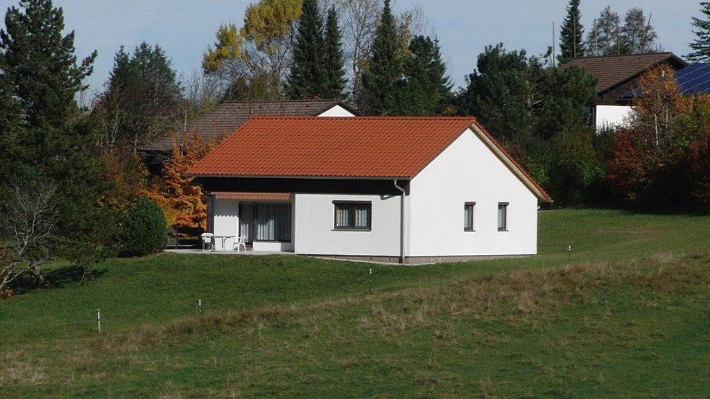 a white house with a red roof on a field at Ferienhaus Gamssteige im Feriendorf Reichenbach G16 in Nesselwang