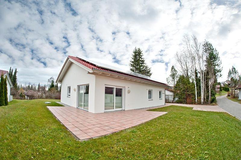 a small white house on a green lawn at Ferienhaus Gamssteige im Feriendorf Reichenbach G7 in Nesselwang