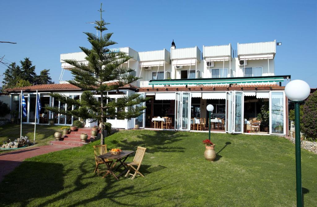 a building with a table and a tree in the yard at Evoikos beach & resort in Livan&aacute;tai