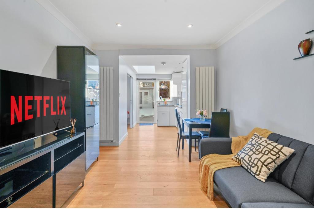 a living room with a couch and a tv at Sunny Side Apartment Wembley in Harrow on the Hill