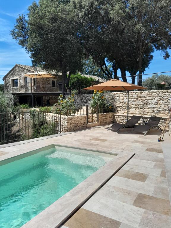 - une piscine avec un parasol et une maison dans l'établissement LA GALINE, à Ménerbes