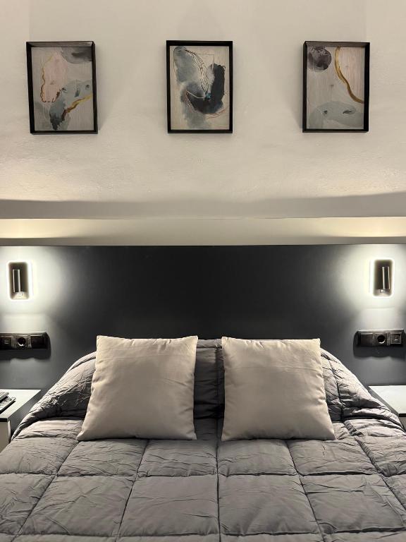 a bedroom with a bed with four pictures on the wall at Caleros 8 - Apartamento 2 in Cáceres