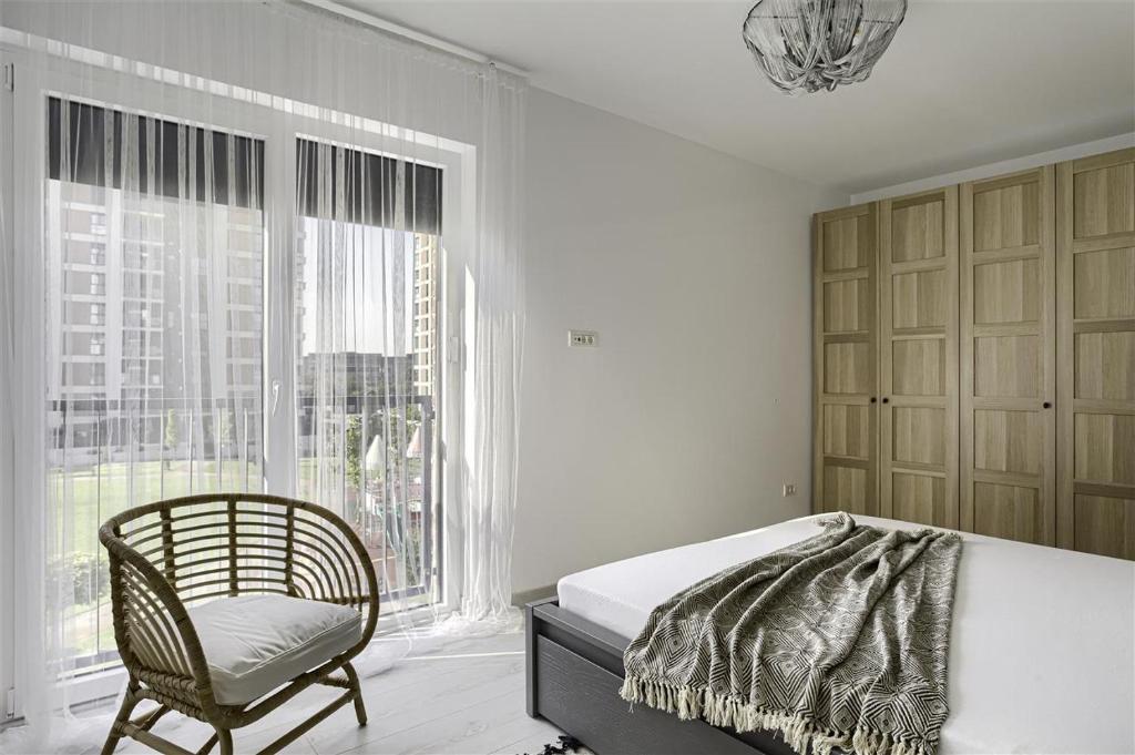 a bedroom with a bed and a chair and a window at Cozy Accommodation - 2 Bedrooms at Adora Park in Arad