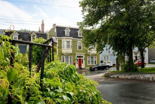 a green house with a red door on a street at The Elizabeth Manor Guesthouse in St. John's
