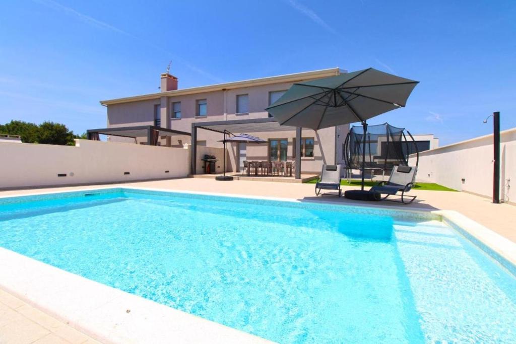 a swimming pool with an umbrella and two chairs at Elegant villa with private pool in Bale in Bale